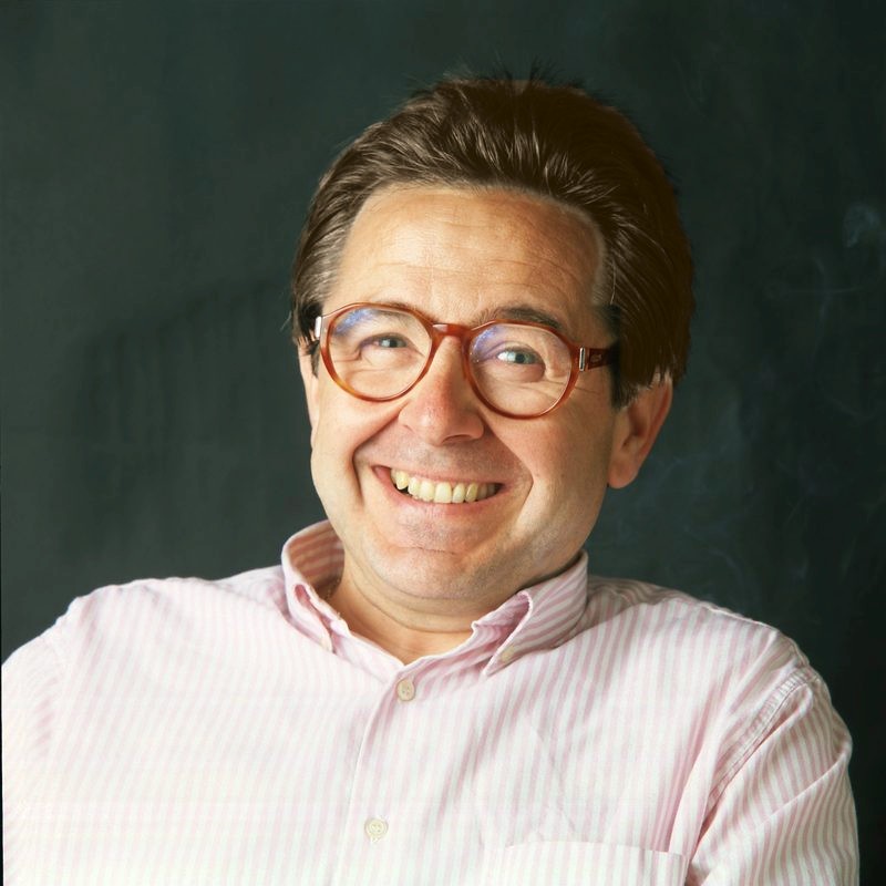 Retrato de José Luis Gimeno Londres sonriendo, con gafas de pasta y camisa de rayas rosas